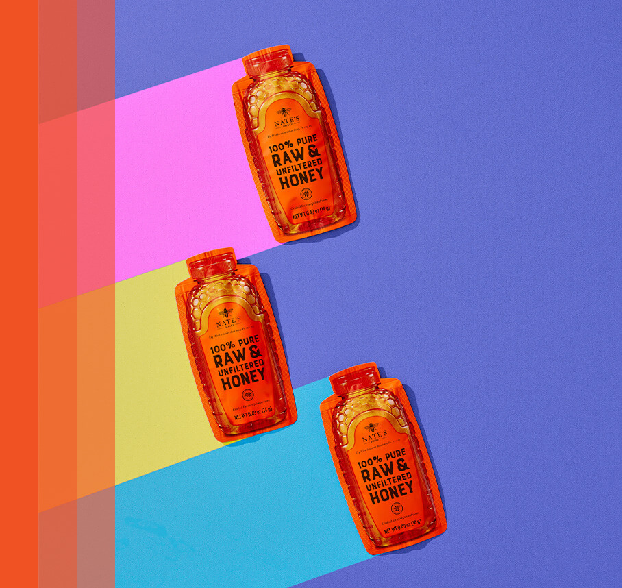 Three Nate's honey minis on a purple background with pink, lime green and blue streaming to the left of the packets.
