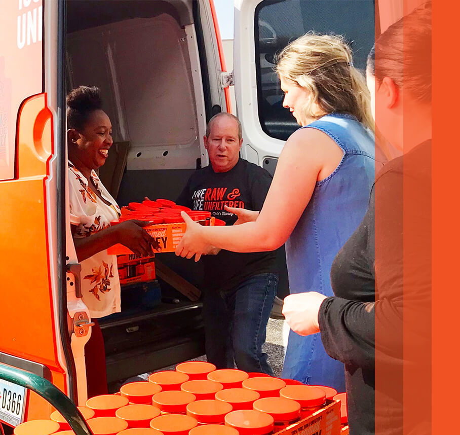 Workers unloading a van, handing boxes of honey to each other.