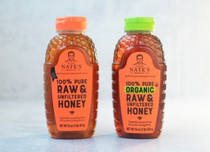 Two bottles of Nate's honey, one labelled raw & unfiltered, the other organic, on a light background.