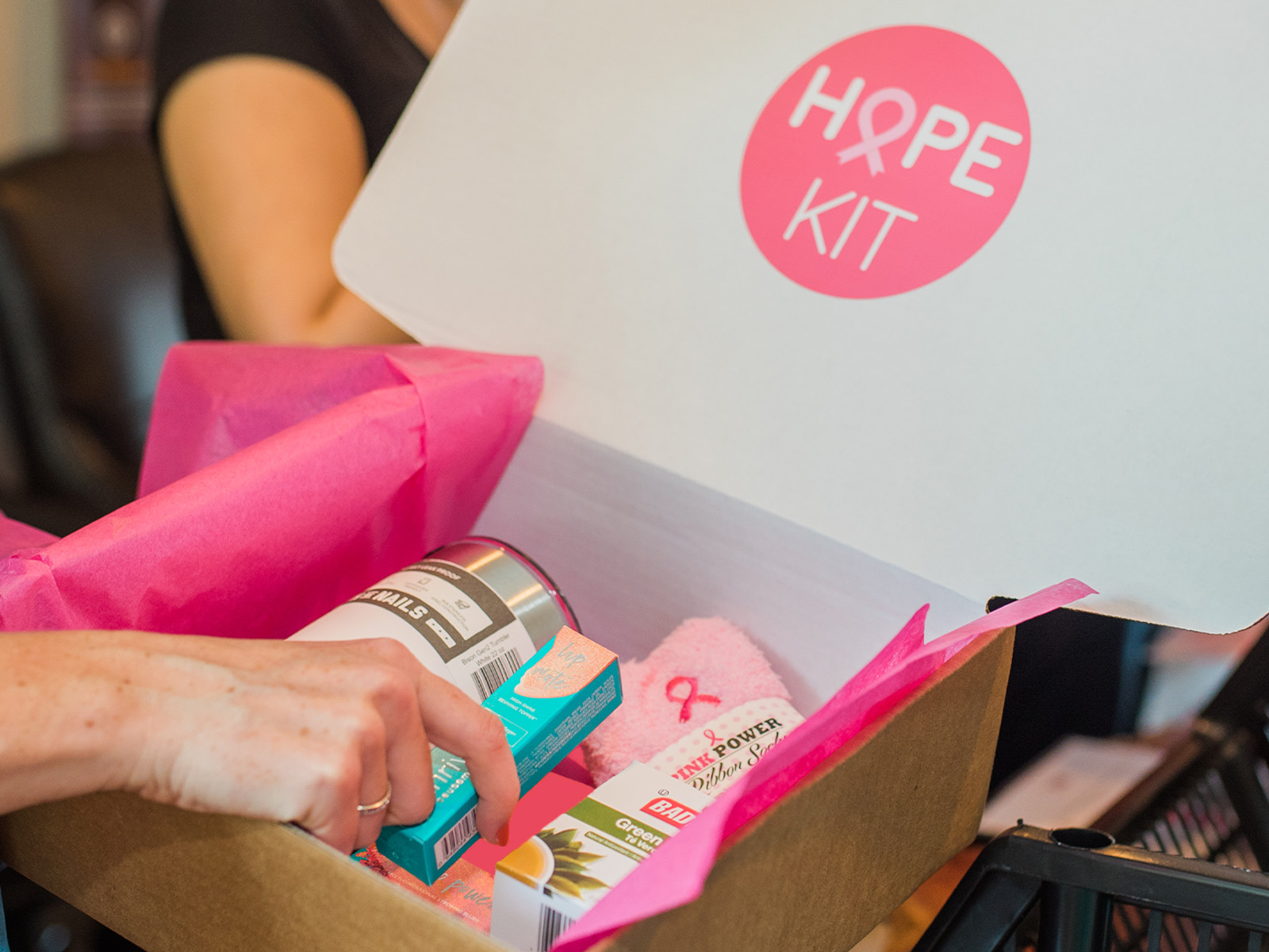 Hope Kit gift box filled with pink tissue paper, wellness items and a pink ribbon support gift.