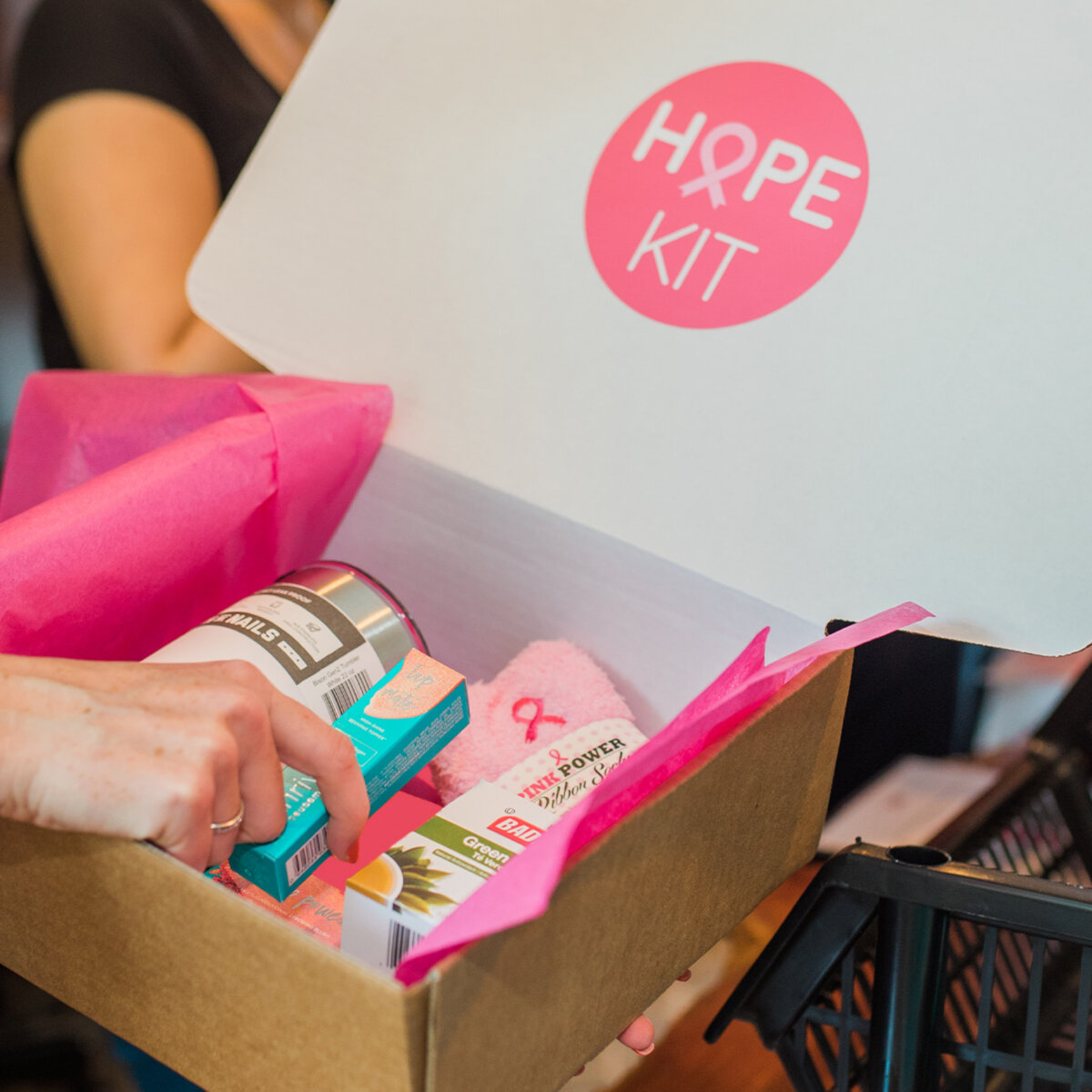 Hope Kit gift box filled with pink tissue paper, wellness items and a pink ribbon support gift.