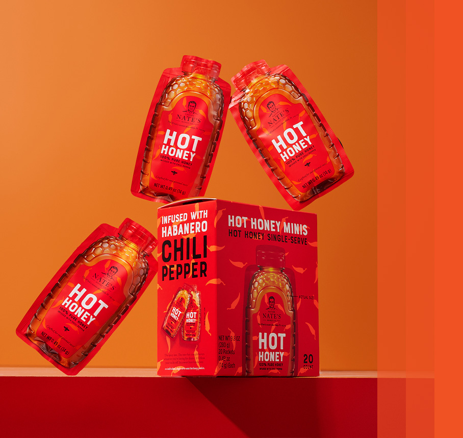 Nature Nate’s Hot Honey Minis in mid-air around their packaging