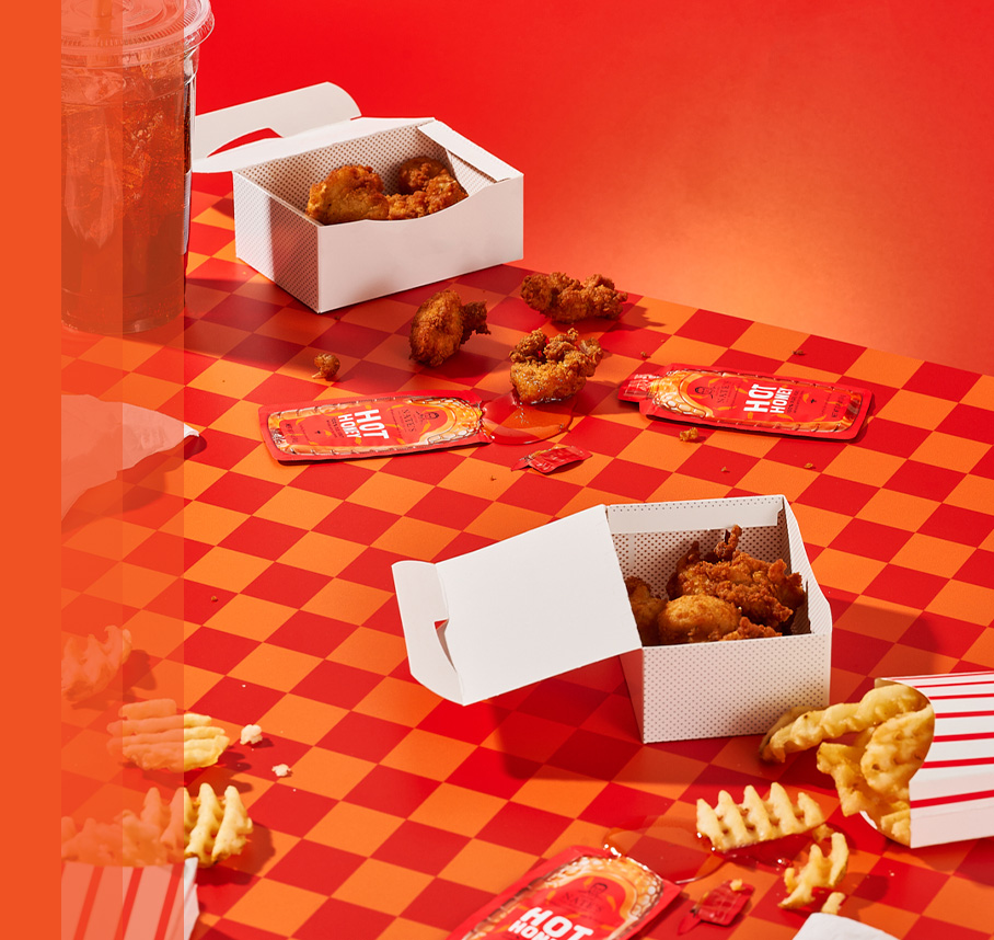 Nate's hot honey minis, chicken nuggets and waffle fries on an orange and red table cloth.