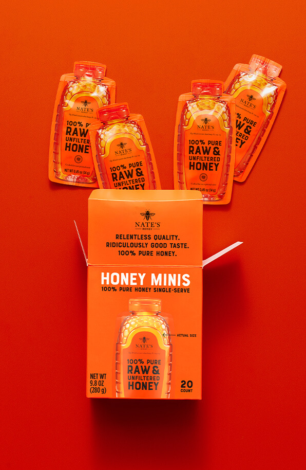 Orange honey minis box with top flap open and four honey mini packets popping out the box top.