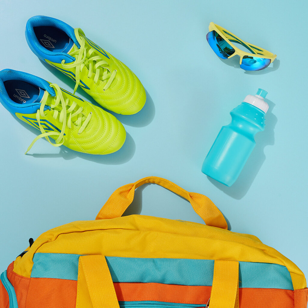 Fitness bag on floor with shoes, water bottle and sunglasses.