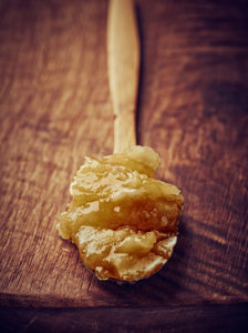 A spoonful of crystallized honey on a wooden background.