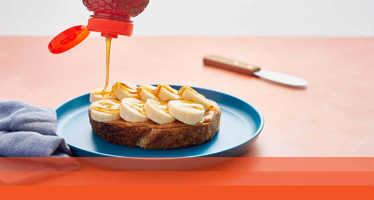 Nate’s honey being drizzled on peanut butter and banana toast.