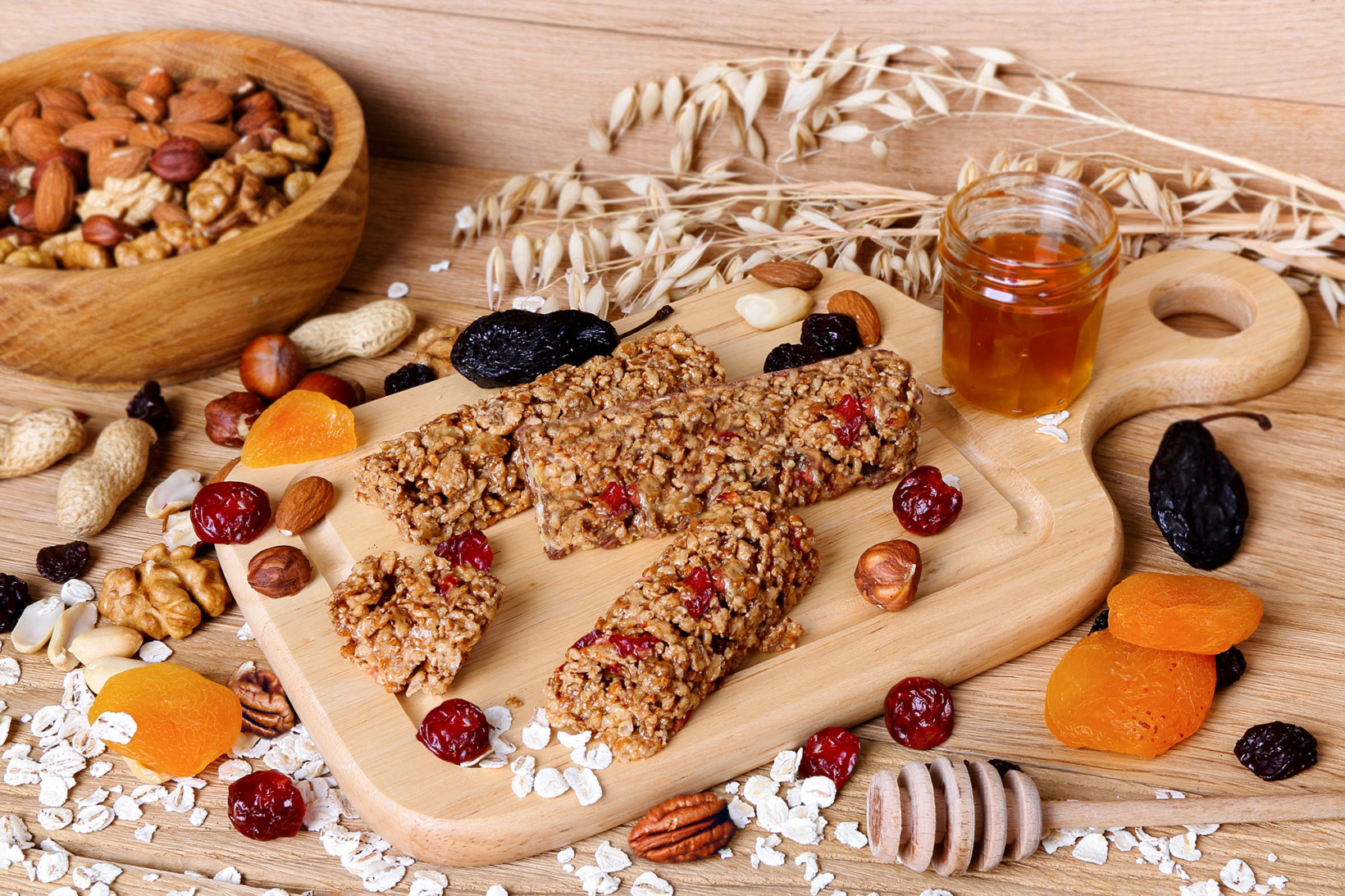 Granola bars with nuts, dried fruits and honey on a wooden board.