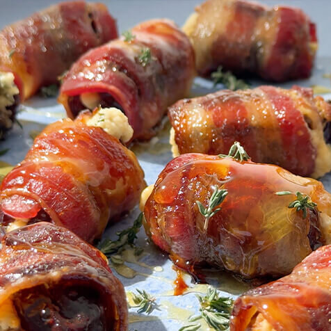 Array of dates stuffed with goat cheese and wrapped in bacon. Garnished with fresh thyme and honey.