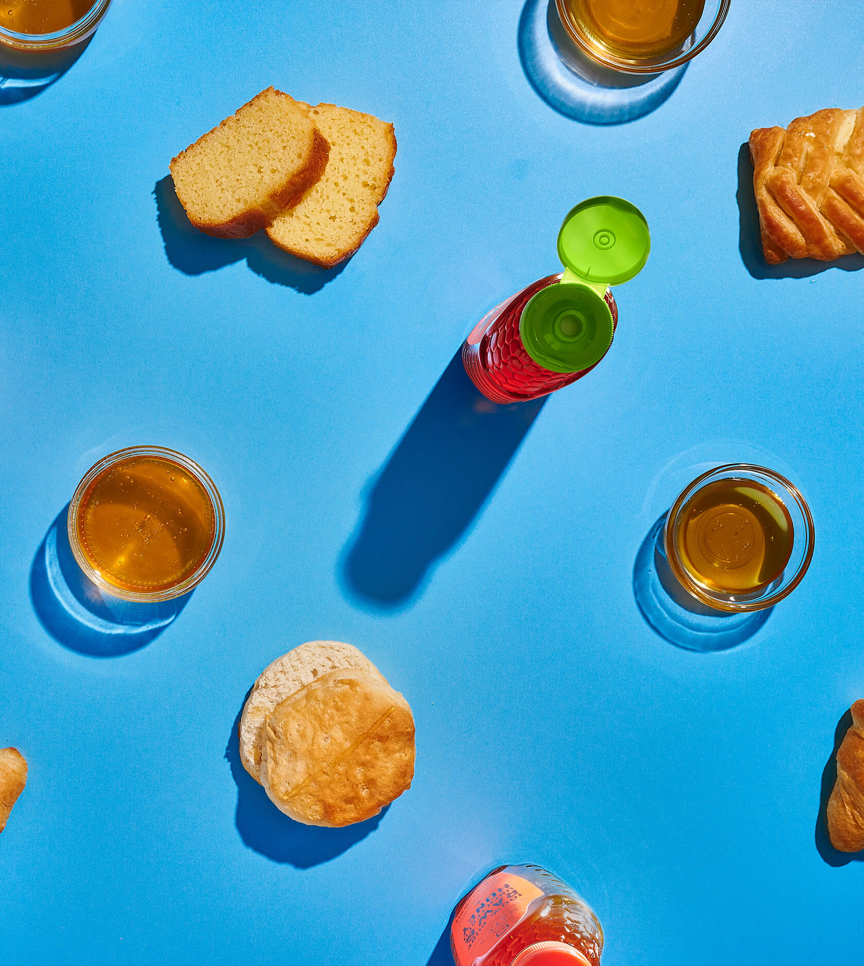 Croissants, biscuits, honey jars, Nate's Organic Honey bottles, coffee, and bread slices arranged on a vibrant blue background.