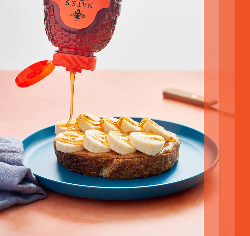 Nate’s honey being drizzled on peanut butter and banana toast.