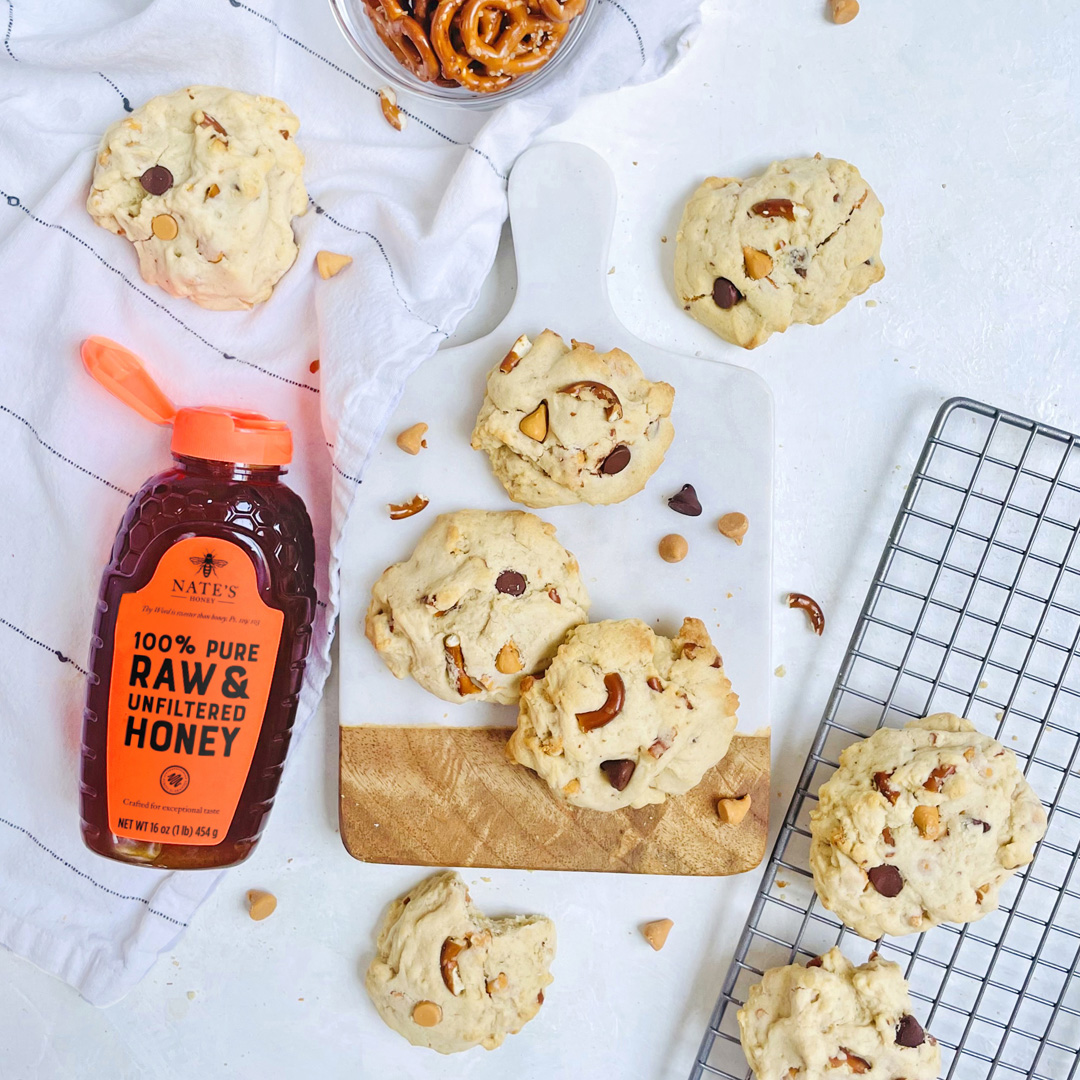 Rice crispy treats made with honey on a striped plate, a bottle of Nate’s Honey, and a glass of milk on marble.