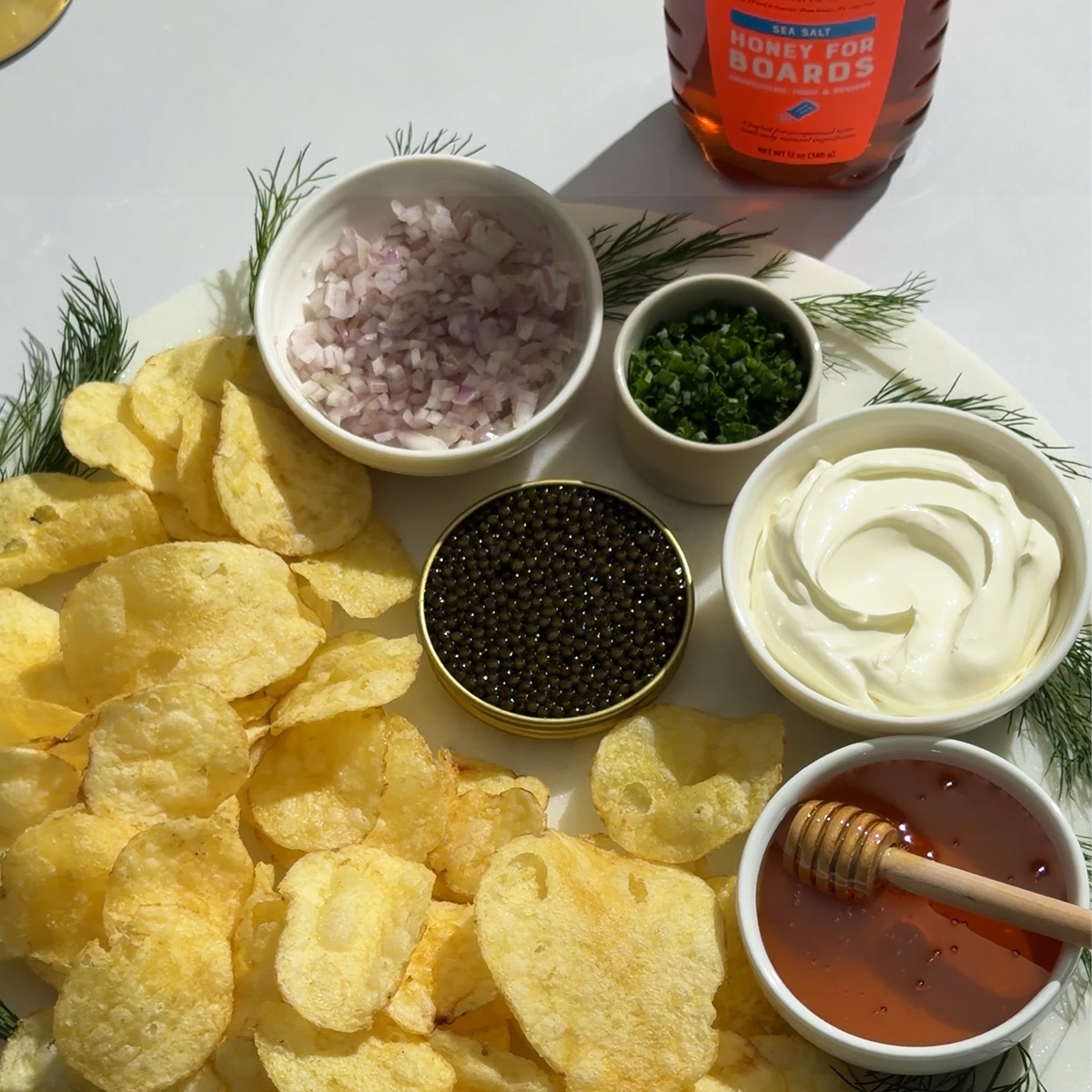 Plate of chips with bowls of with crème fraîche, fresh shallots, chives and caviar.