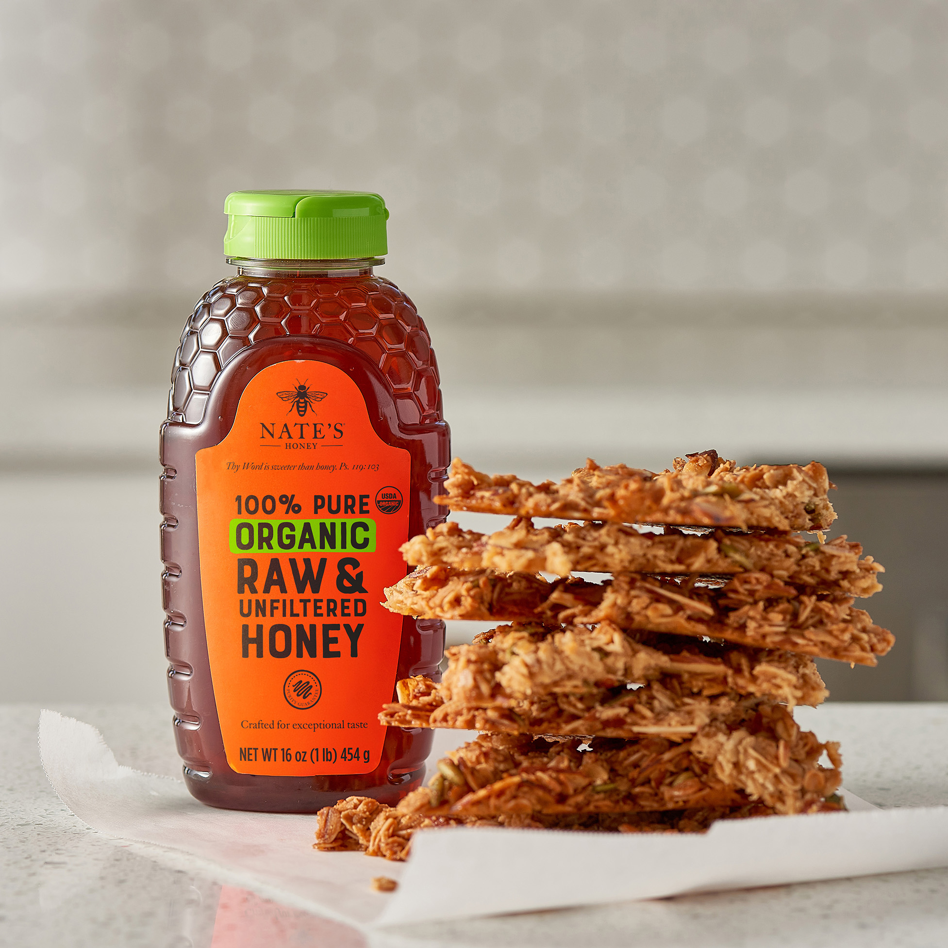 Nate's Organic Honey next to stack of honey almond granola bark
