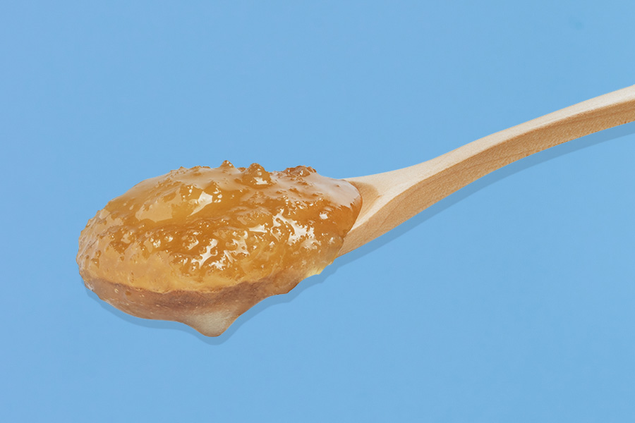 Golden granulated honey with a coarse, glistening texture.