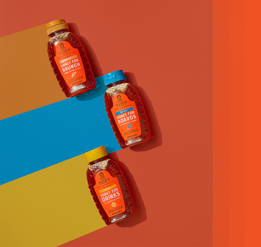 flavored honey bottles on orange background with brown, blue and yellow stripe