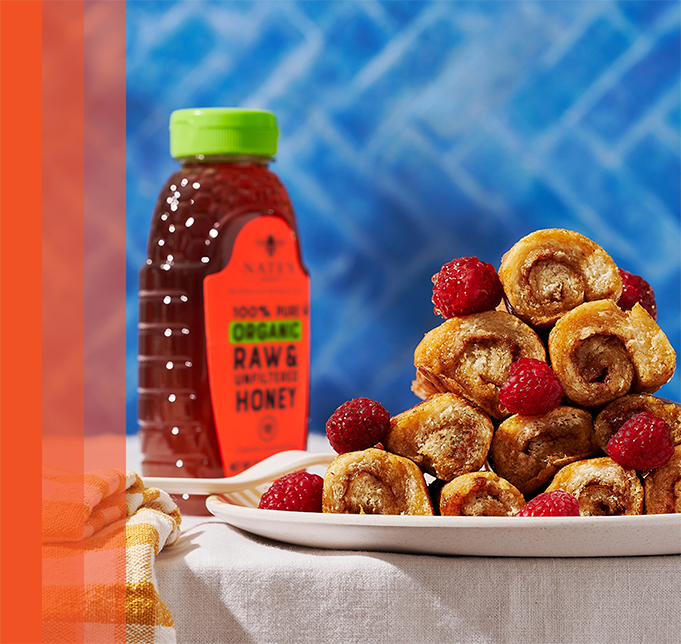 French toast roll ups on plate next to organic honey bottle.