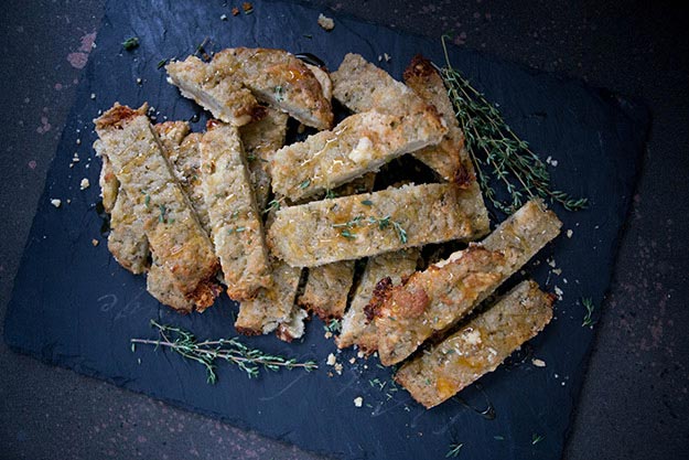 Crispy gorgonzola puffs with fresh thyme, drizzled with honey on a slate board, dark textured background.