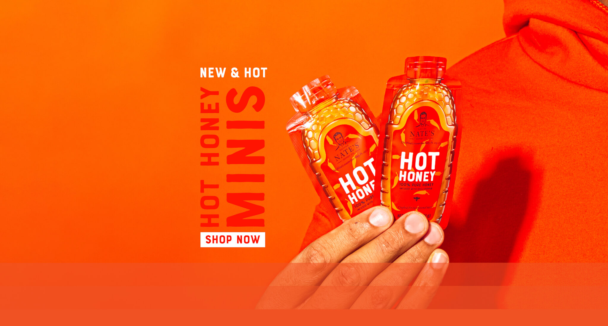 Two hot honey minis held in a hand against an orange background, with bold text reading 'Hot Honey Minis this link will open in a new window.