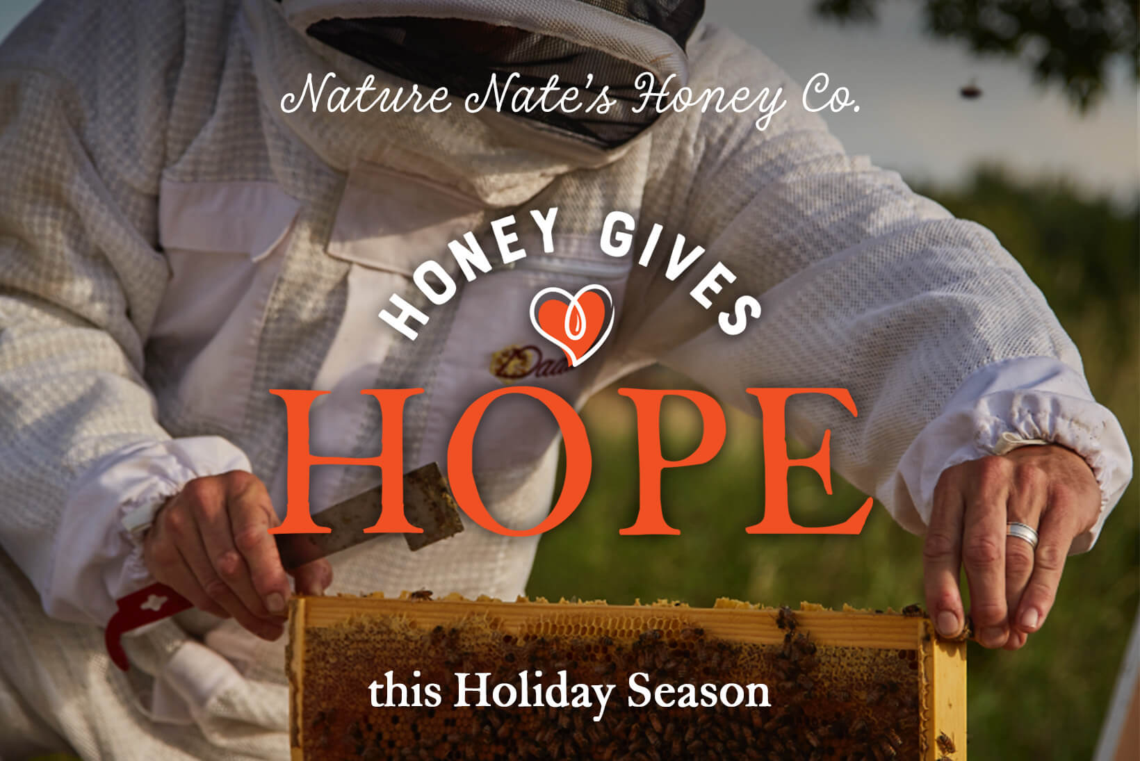 A beekeeper holding a honeycomb frame with Nature Nate's Honey Co., HONEY GIVES HOPE this Holiday Season overlay text.