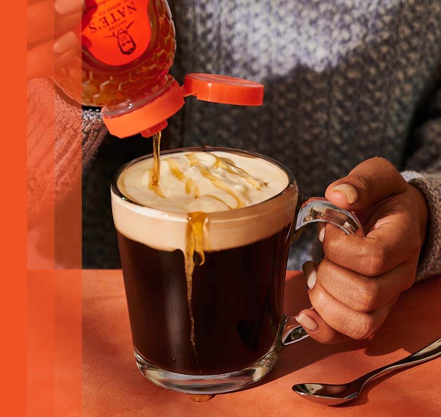 Honey being drizzled into a frothy coffee drink.