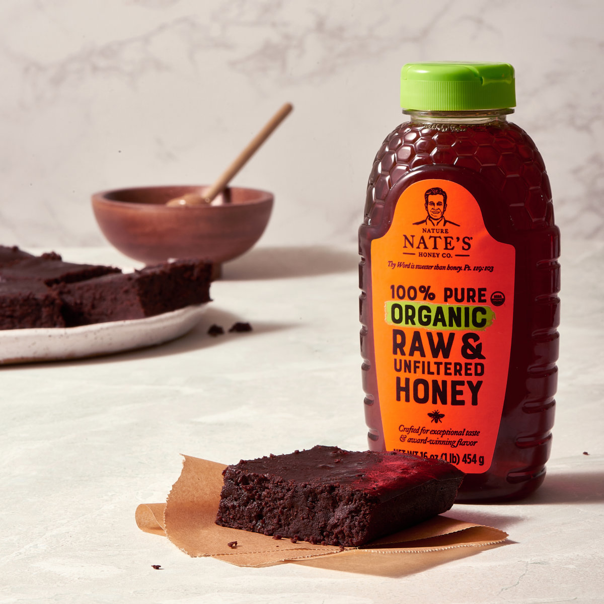 Brownies with a bottle of Nate's organic raw honey and a honey dipper in the background.