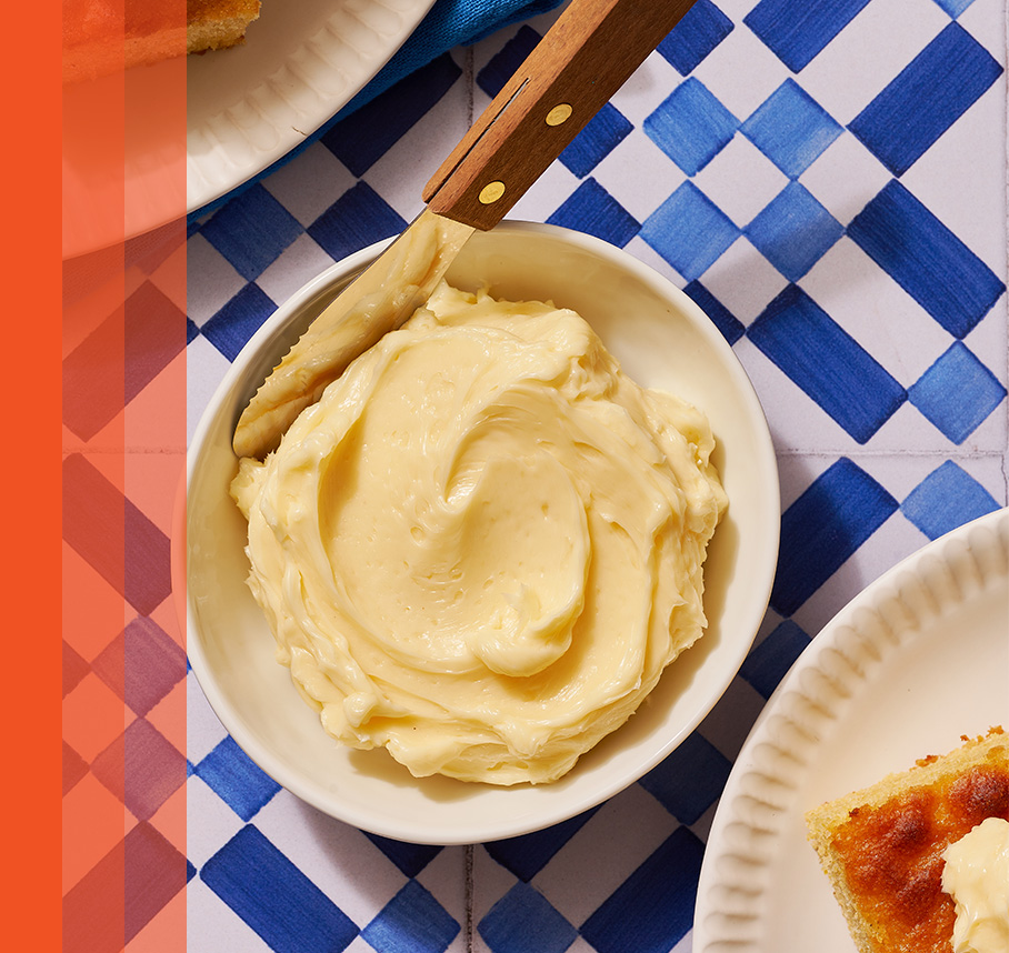 Bowl filled with honey butter spread on white and blue checkered tablecloth.