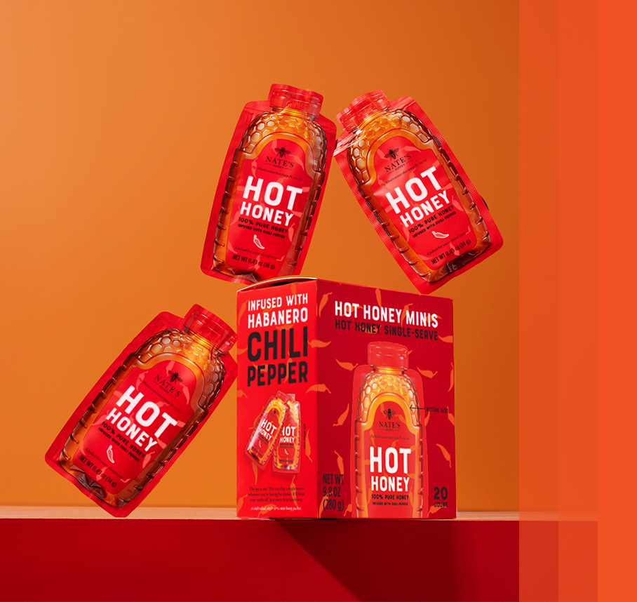 Nate’s Hot Honey Minis in mid-air around their packaging.