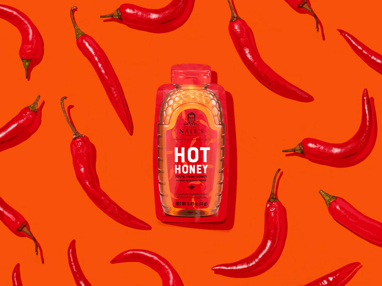 Nate’s Hot Honey bottle surrounded by red chili peppers on a vibrant orange background.