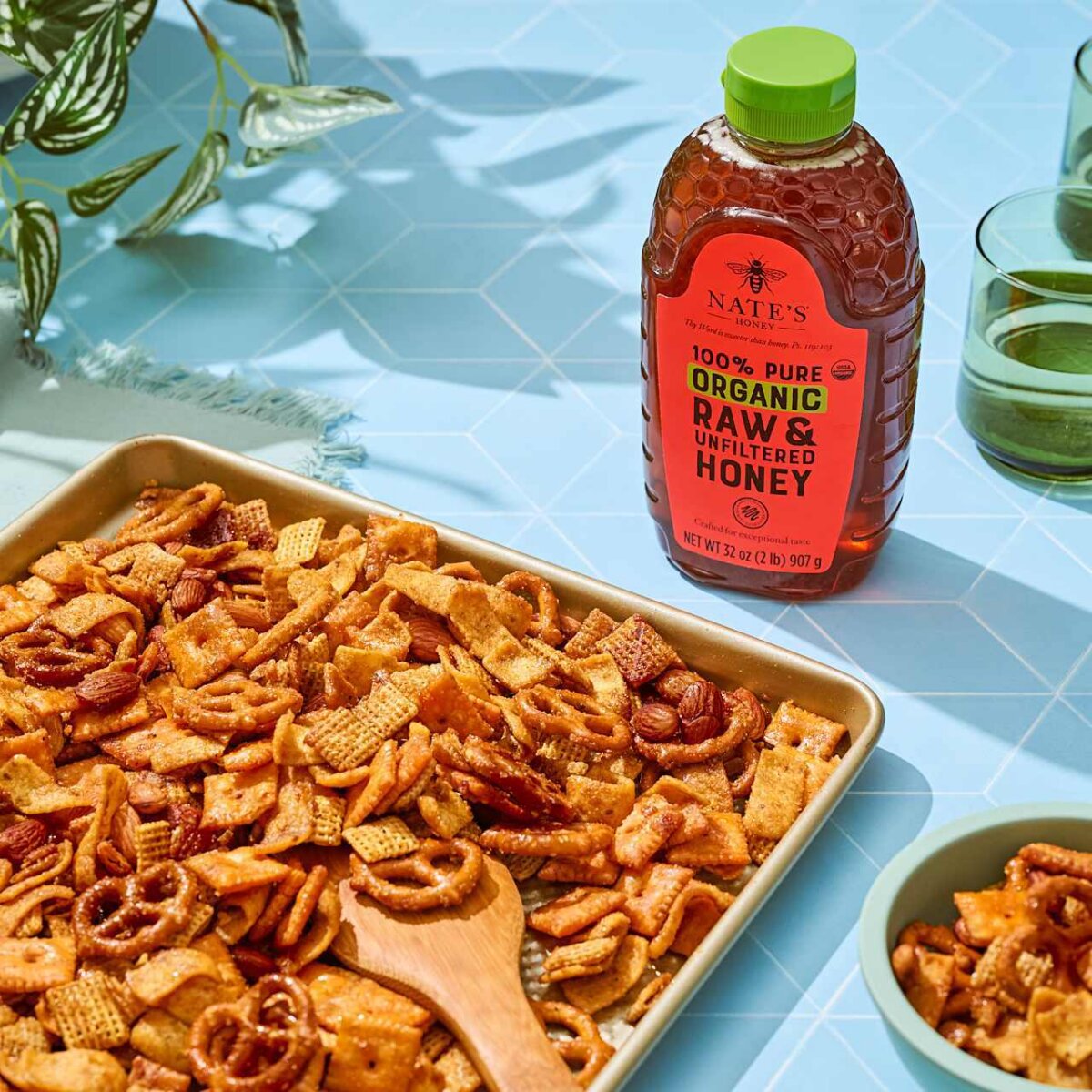 Baked sweet‑and‑savory snack mix with pretzels, cereal squares, crackers and almonds spread on a baking sheet.