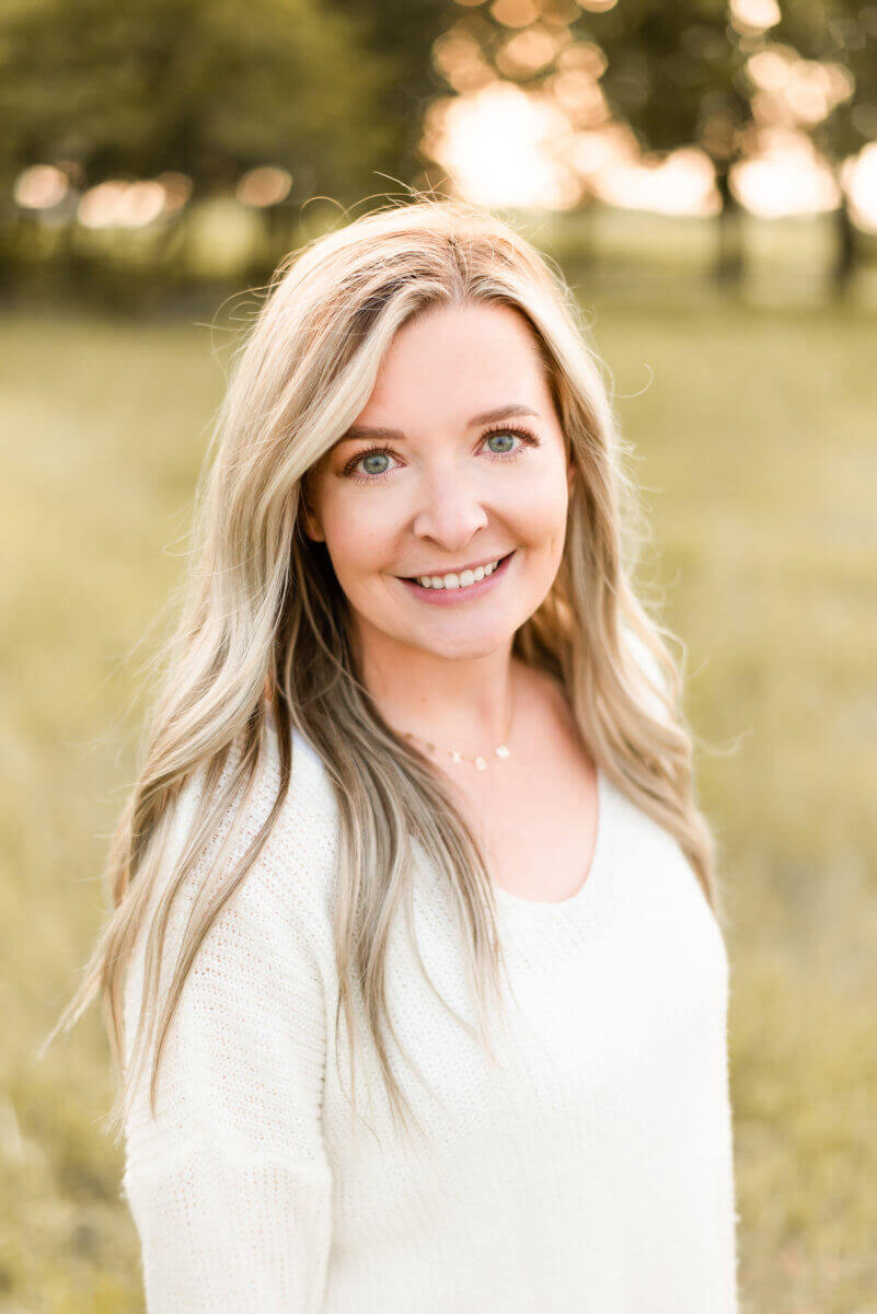 Nate's director of shopper marketing wearing a white sweater and standing in a sunlit field.