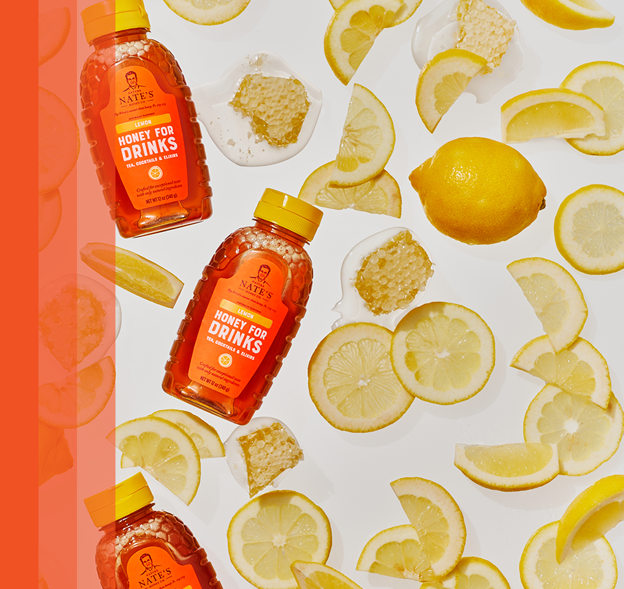 Lemon Flavored Honey bottle spread with lemon slices and honey comb surrounding it.
