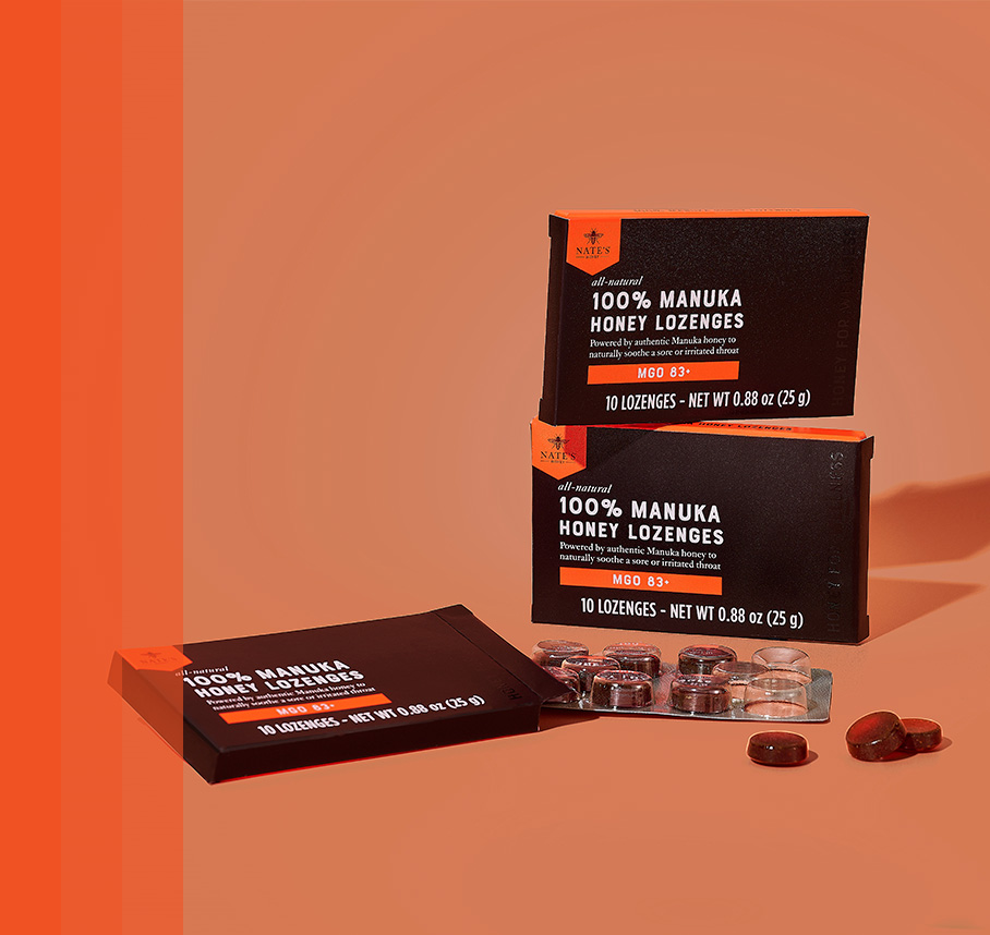 Boxes of Nate’s 100% Manuka Honey Lozenges with individual lozenges displayed on a warm orange background.