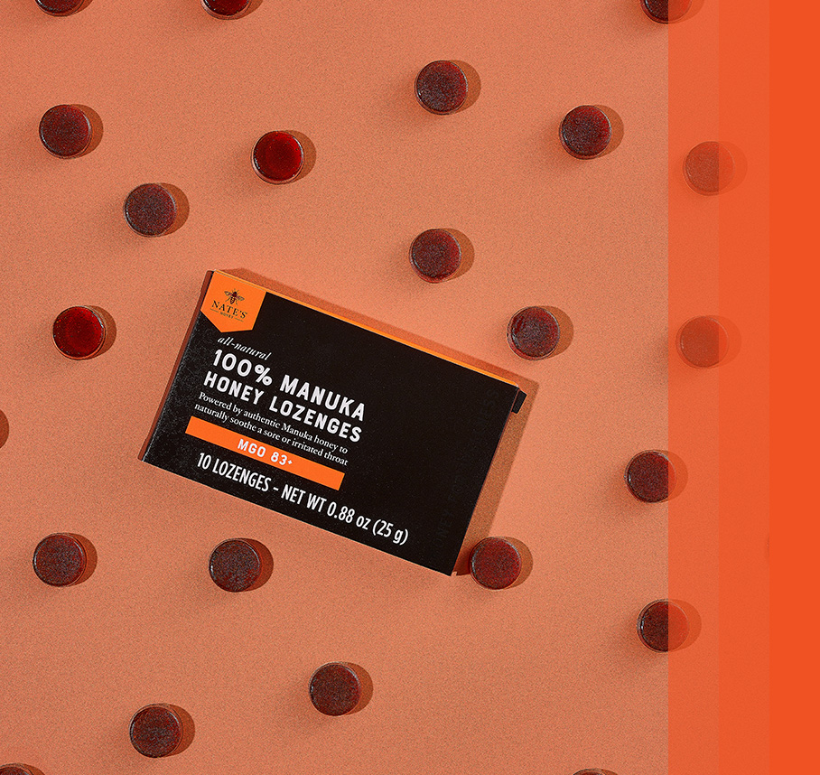 Box of Nate’s 100% Manuka Honey Lozenges surrounded by individual lozenges on an orange background.