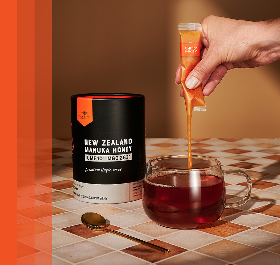 Hand squeezing Manuka Mini packet into mug od tea.