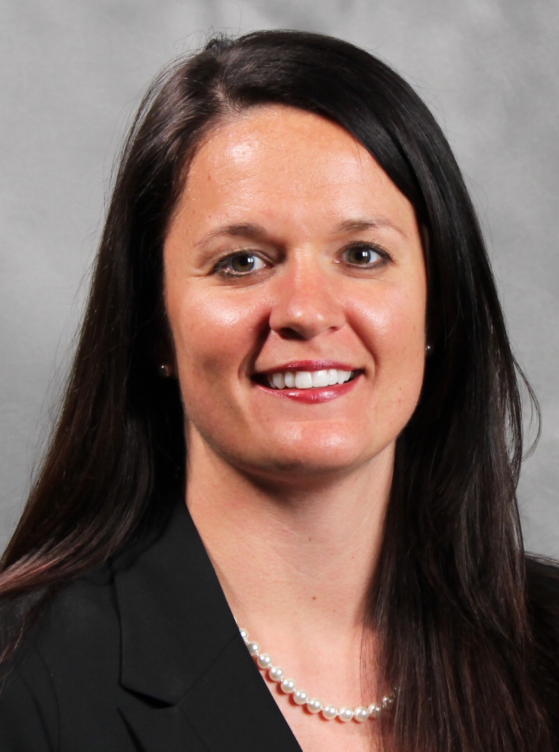 Female Nate's employee with long hair and a black blazer, with a pearl necklace.