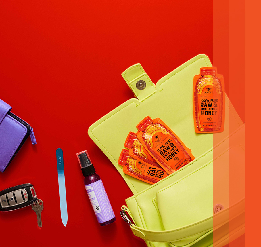 Green purse with front flap open to show four honey minis and other purse essentials: keys, wallet and chapstick.