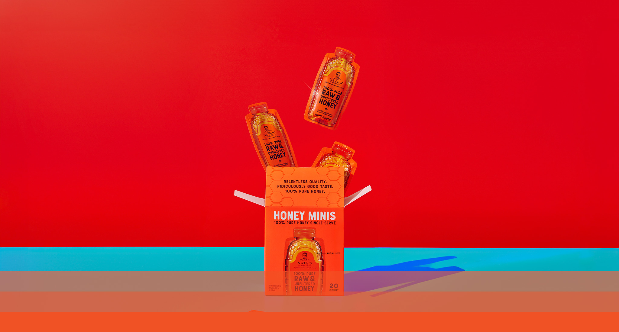 Orange honey minis box with top flap open and three honey mini packets popping out the box top.
