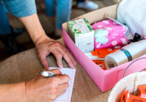 A person's hands packing a HOPE KIT box with various items including Nate’s honey minis.