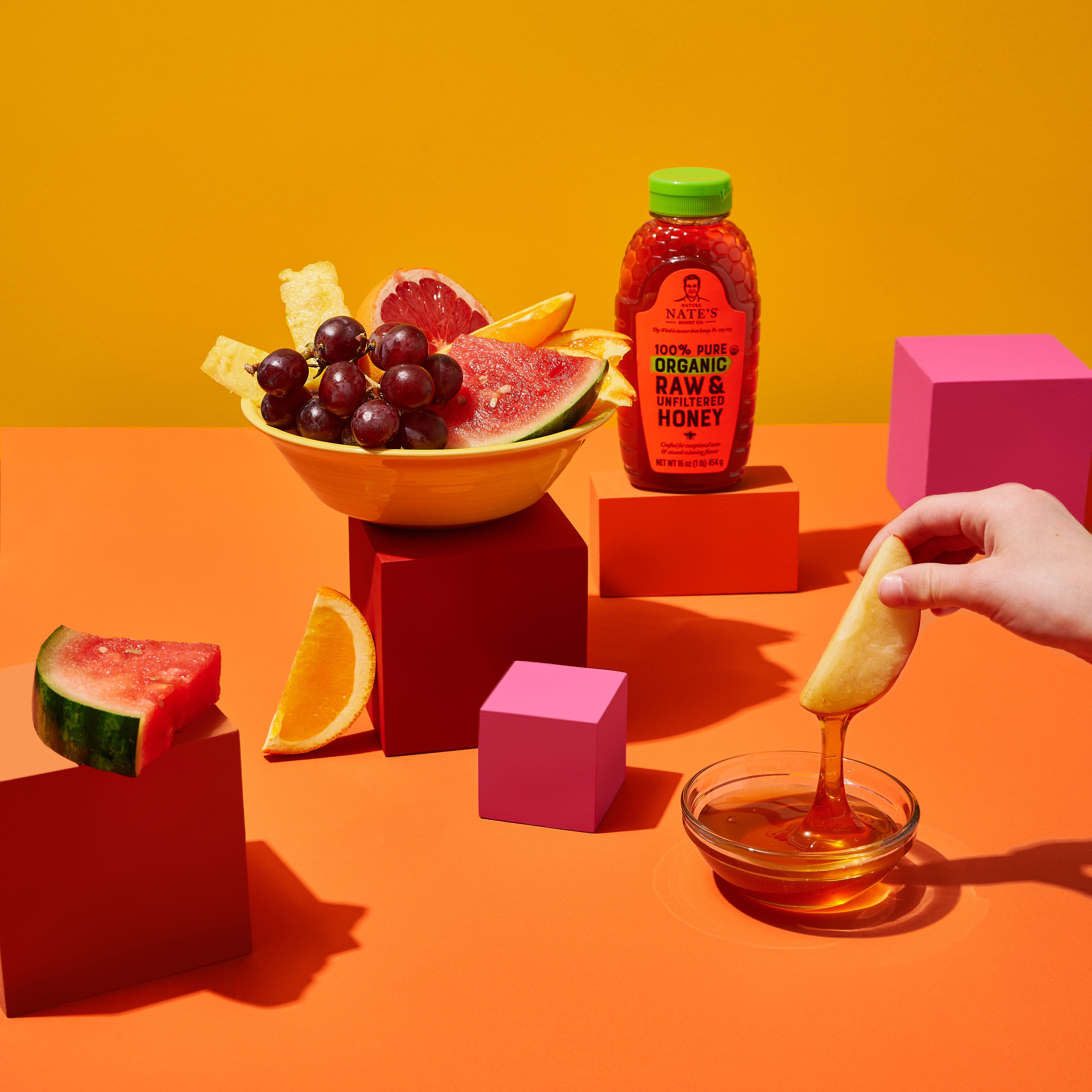 Hand dipping apple into honey.