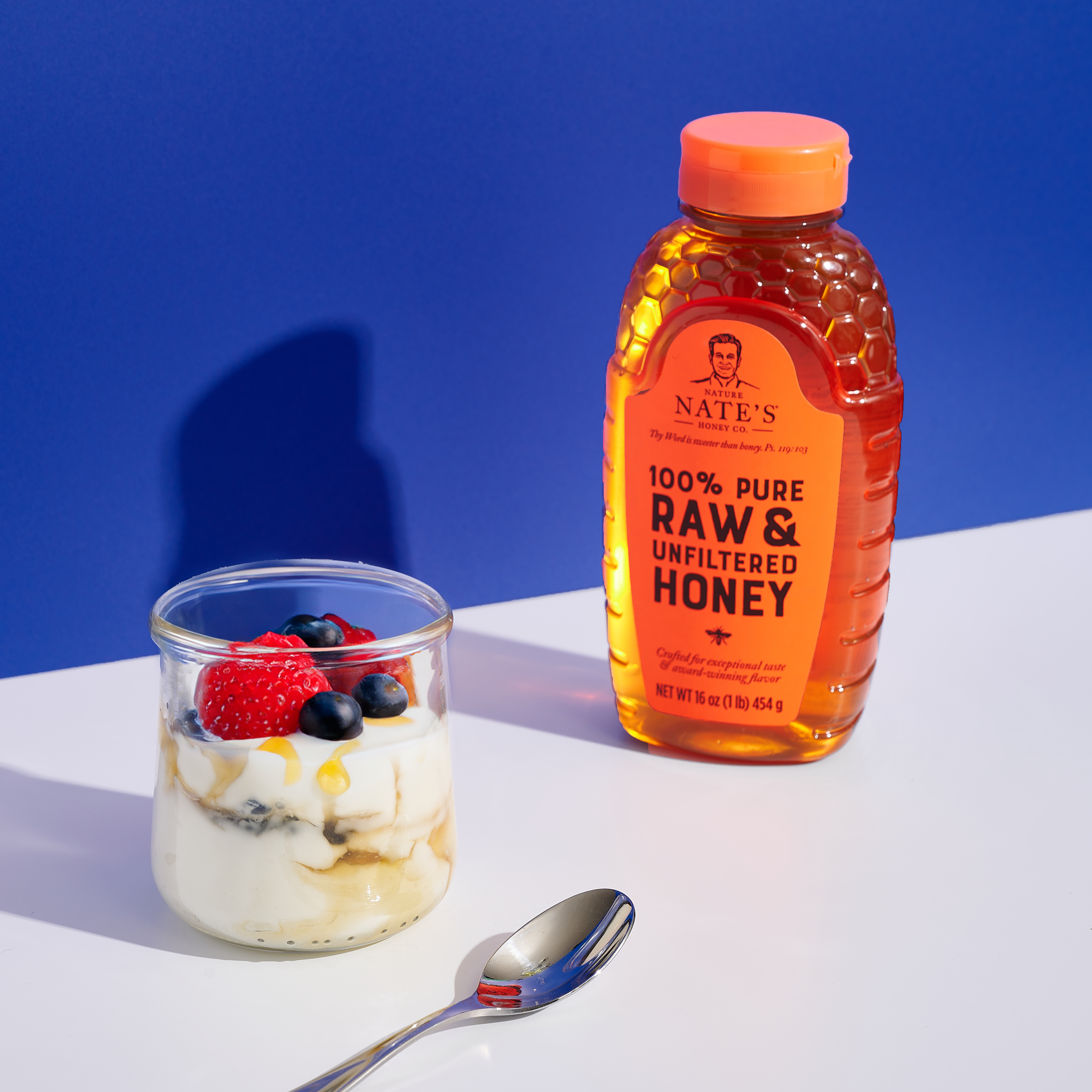 Nature Nate's Classic Raw & Unfiltered Honey paired with a yogurt parfait topped with fresh berries.