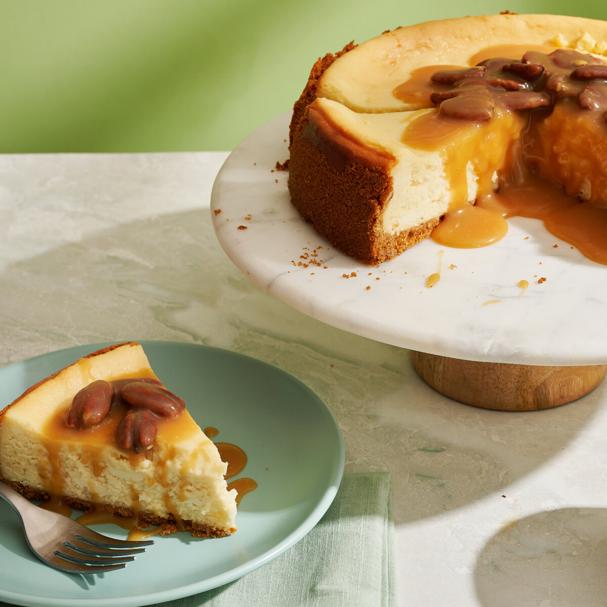 A slice of butter pecan cheesecake on plate with green background.