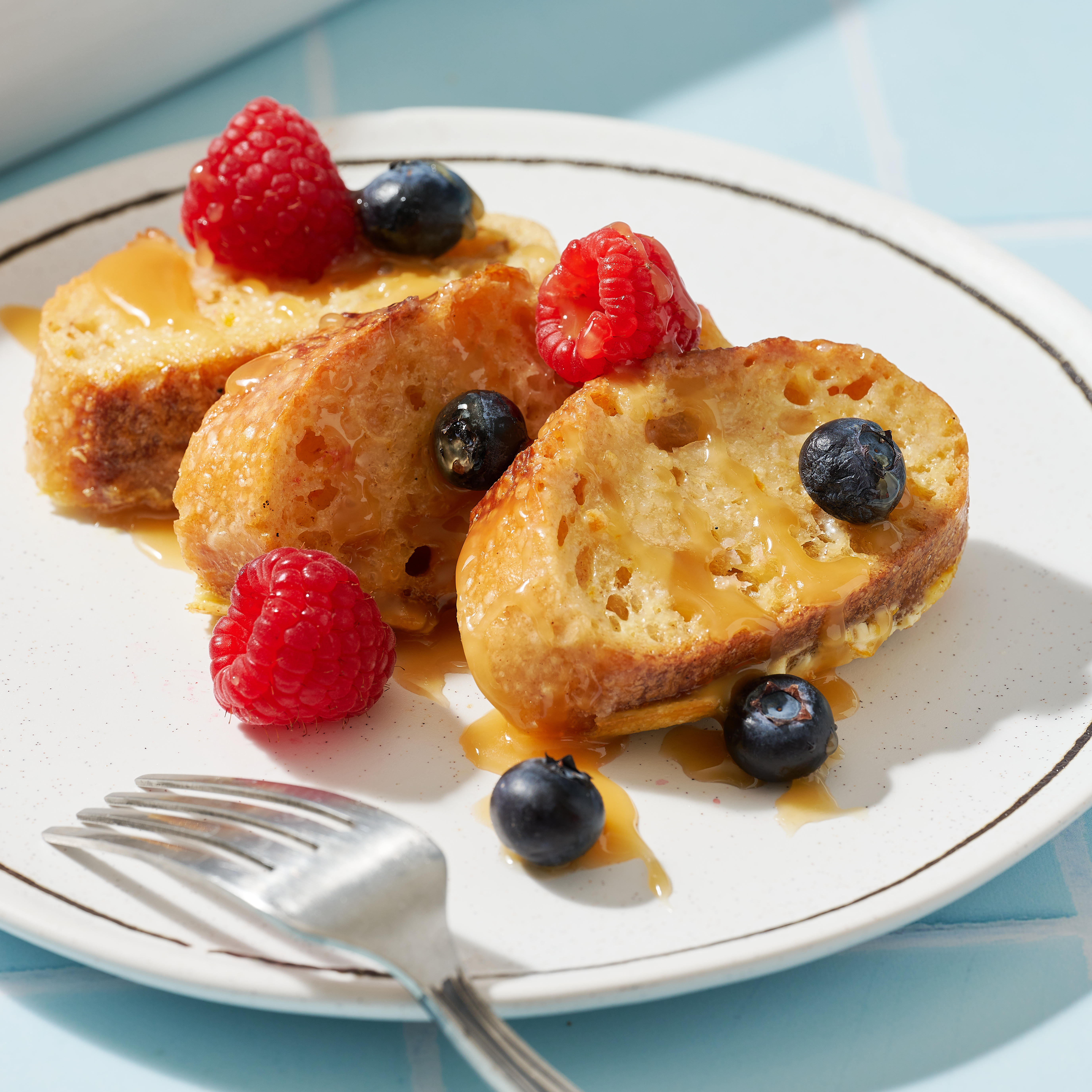 Plate of French toast topped with berries and honey.