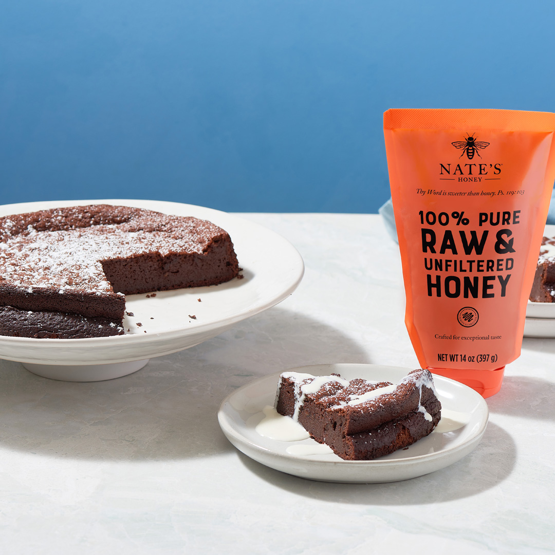 A chocolate cake dusted with powdered sugar next to a Nate's Honey pouch.