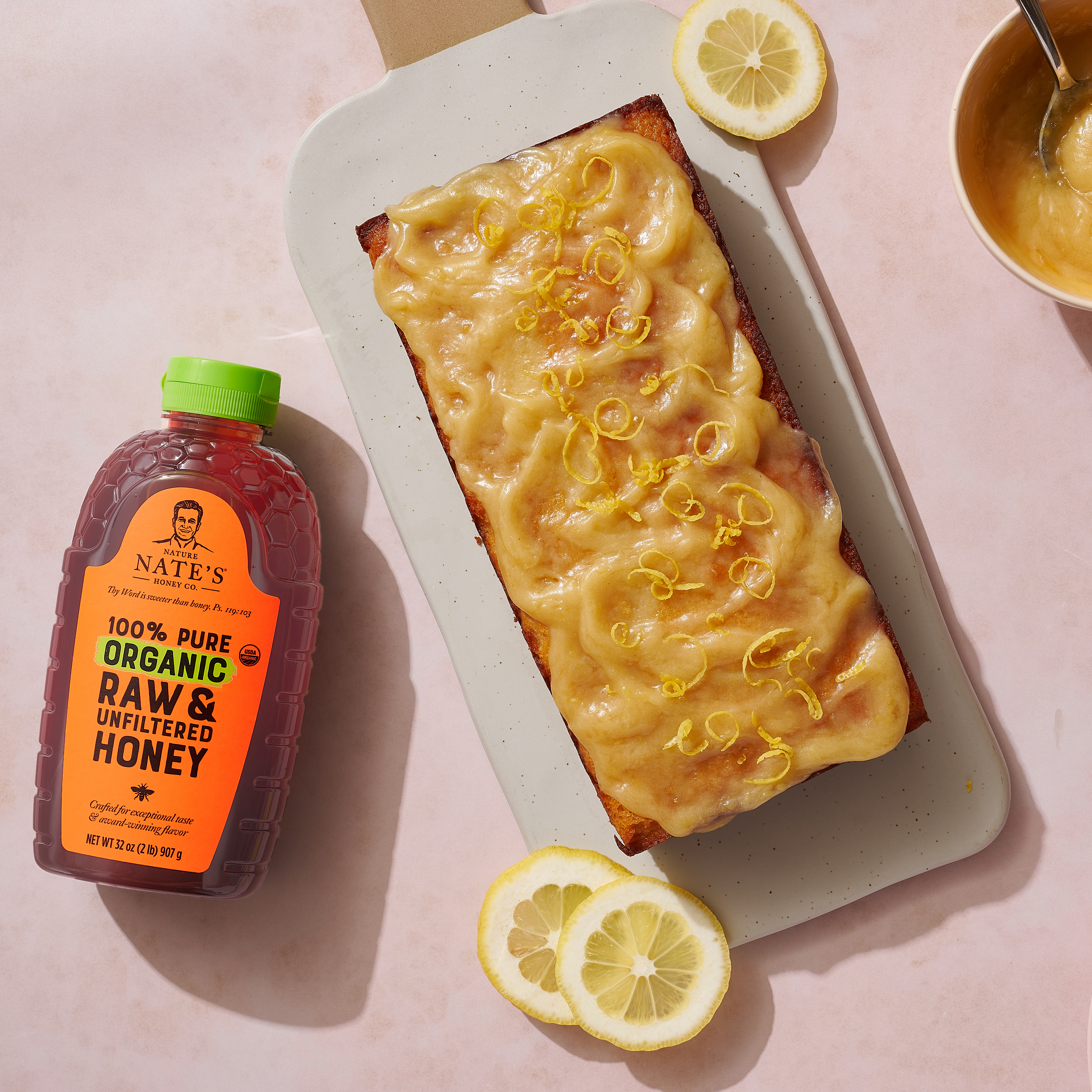 Honey lemon loaf with a cup of coffee and a bottle of Nate's Organic Honey.