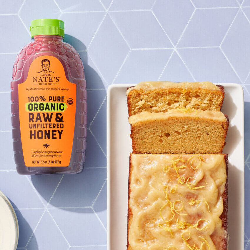 Honey lemon loaf with a cup of coffee and a bottle of Nate's Organic Honey.