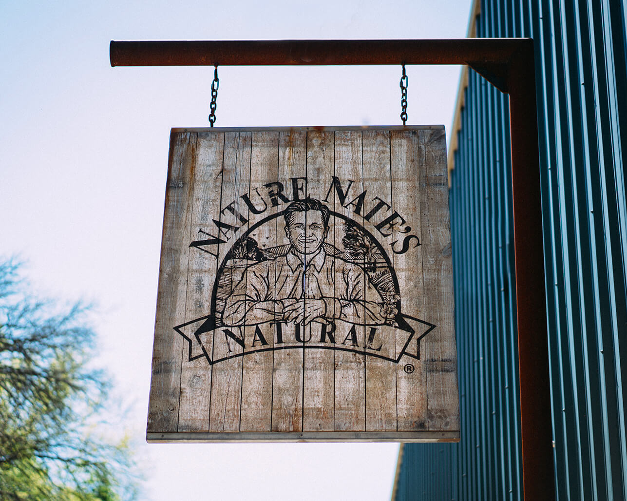 Nate's natural wooden sign hanging outdoors.