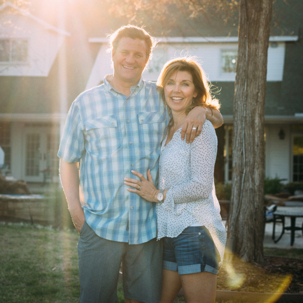 The man Nature Nate and his wife embracing outdoors with sun setting behind them, creating a warm glow.