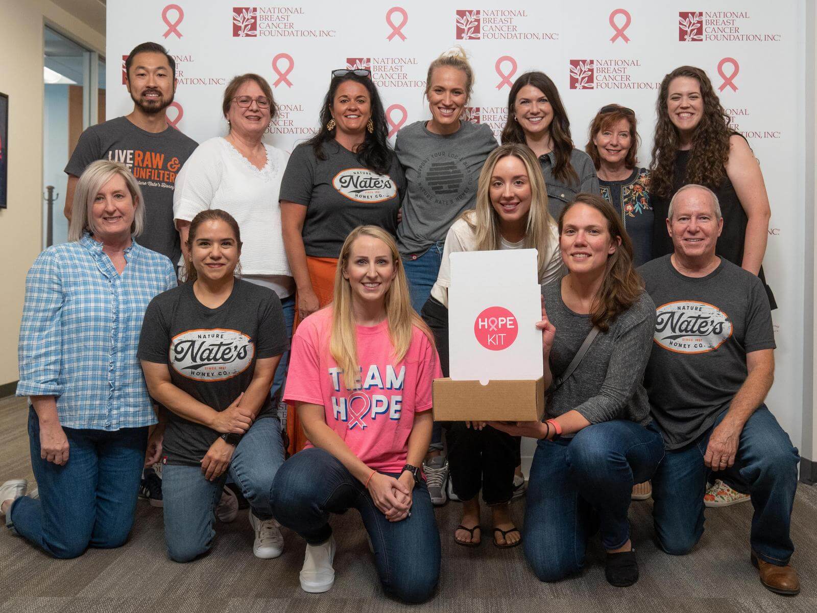 A group of Nate’s employees wearing shirts with Nate's and I AM HOPE logos holding a box with HOPE KIT on it.