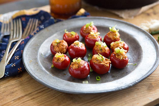 Stuffed cherry peppers on a metal plate with a rustic backdrop.